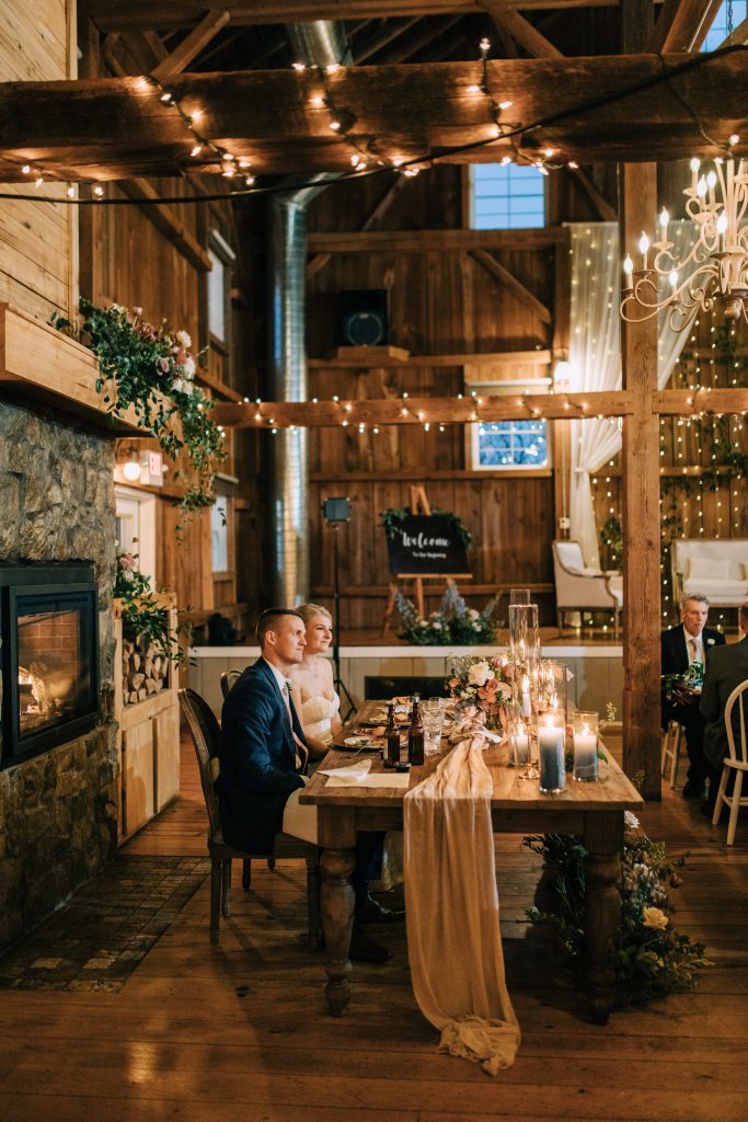 The bride and groom sitting at their sweetheart table in Wisconsin barn wedding venue