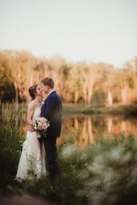 Bride and groom smile at each other near the pond at their Wisconsin outdoor wedding venue